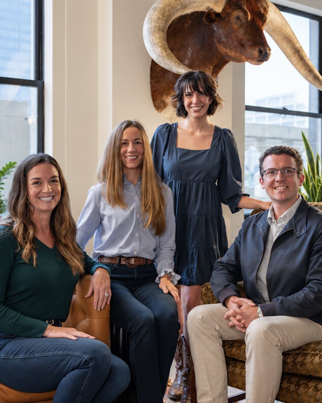Four members of the Whale Song team smiling together in a sunlit loft office.